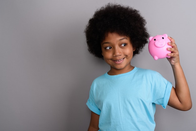 Young cute African girl against gray wall