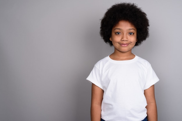 Young cute African girl against gray wall