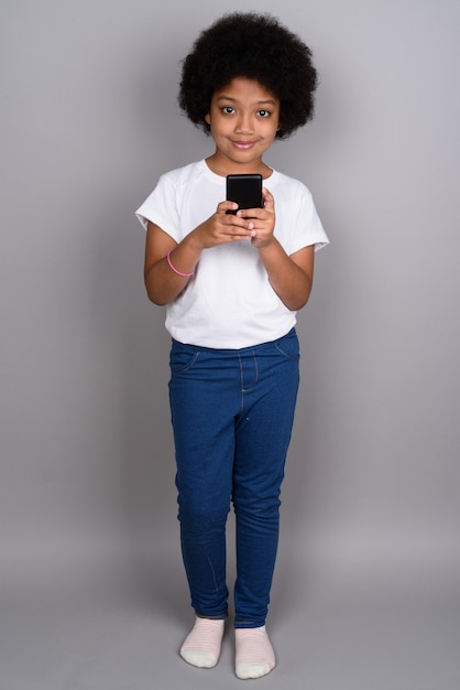 Young cute African girl against gray wall