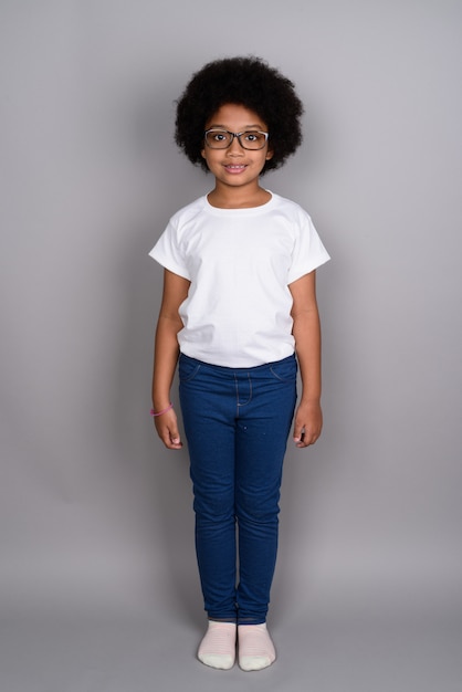 Young cute African girl against gray wall