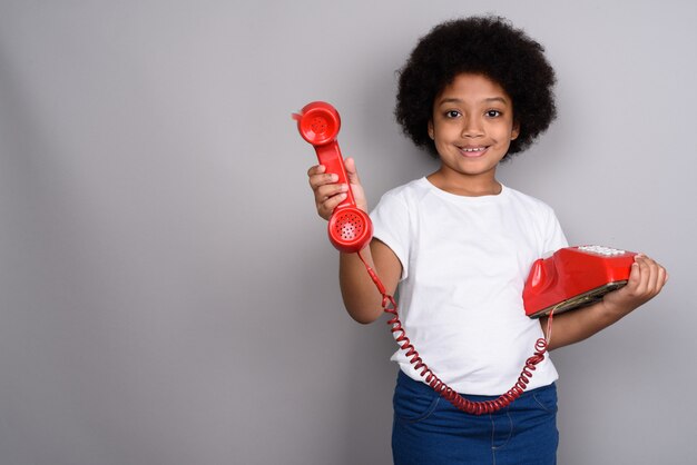 Young cute African girl against gray wall