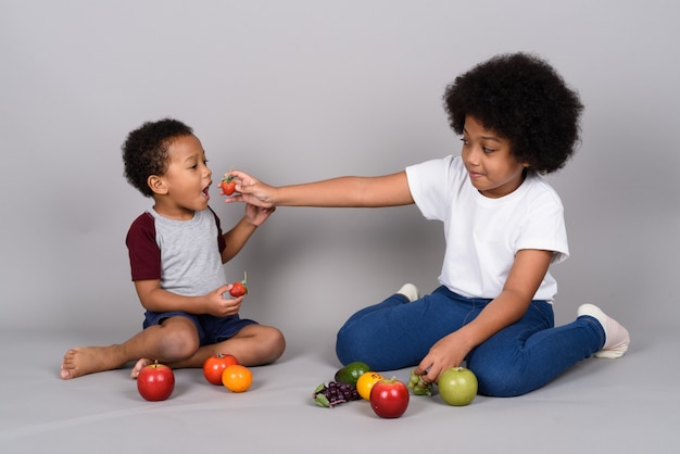 Young cute African siblings together against gray wall