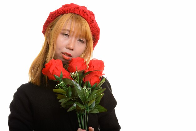 Young cute Asian woman holding red roses looking sad