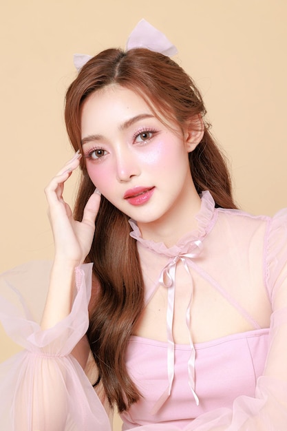 사진 분홍색의 우아한 드레스를 입은 귀여운 젊은 아시아 여성 한국 스타일의 메이크업 보습 부드러운 베이지 바탕에 완벽한 피부 얼굴 치료 화장품 성형수술