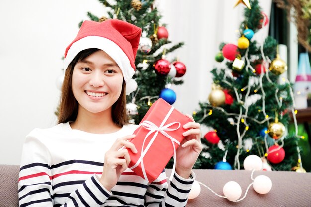 Young cute asian woman smiling and holding red gift box at Christmas party