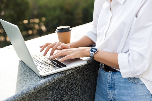 Young cute beautiful woman walking outdoors using laptop computer