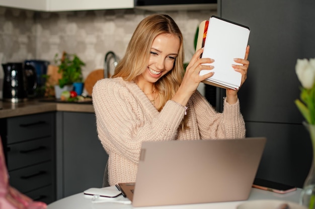 Young cute blonde person beautiful woman with books is happy to pass exams online study home office
