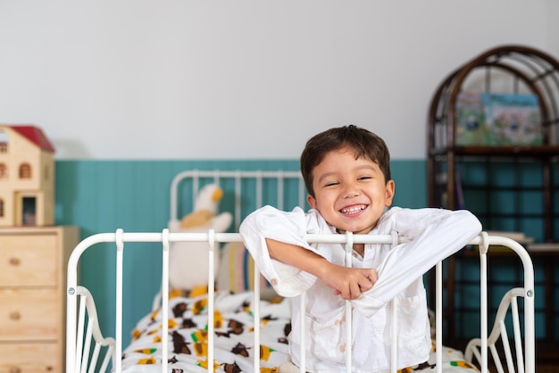 Young cute boy relaxing at his bed while smiling