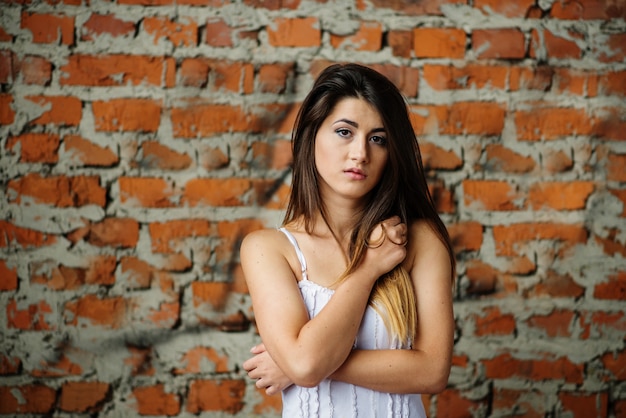 Young cute brunette girl background brick wall.