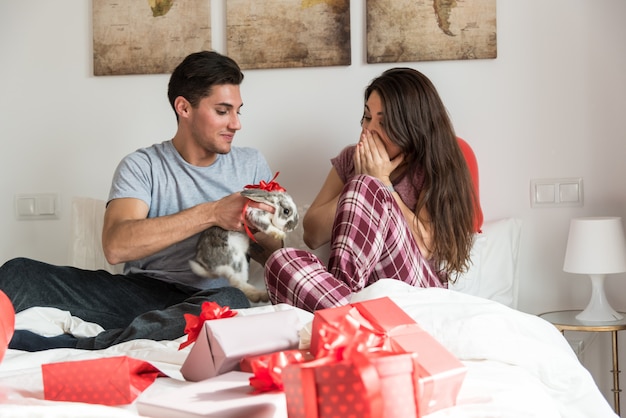 Young cute couple giving a bunny as a gift