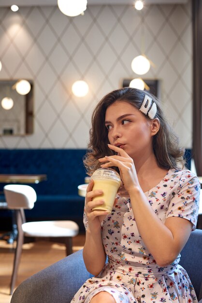 Young cute girl in dress drinking milkshake