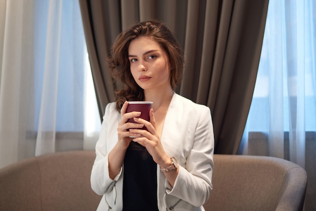 Young cute girl drinking coffee in cafe