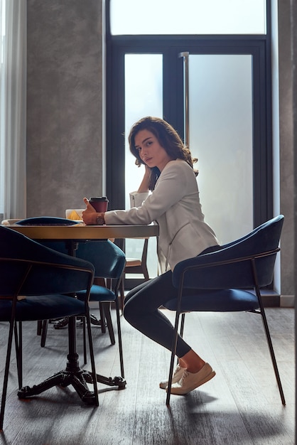 Young cute girl drinking coffee in cafe