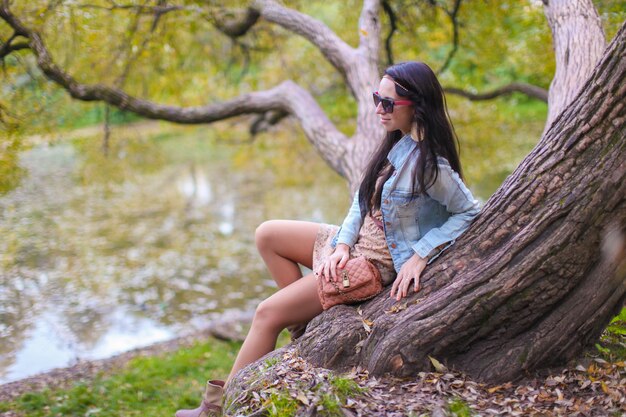 Young cute girl enjoying holiday in autumn park near the lake