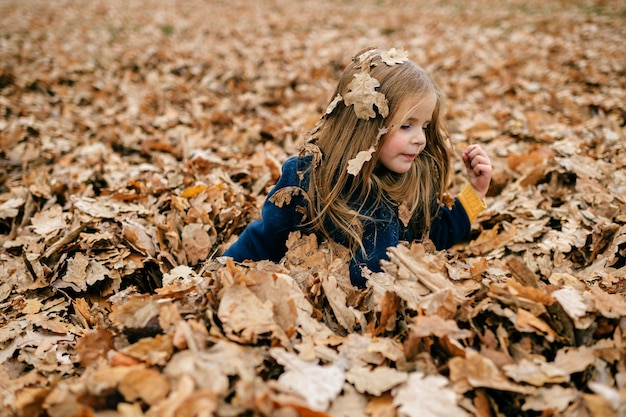 A young cute girl playing in leaves