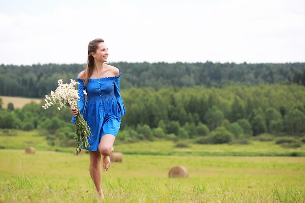 Young cute girl run in a field at sunset