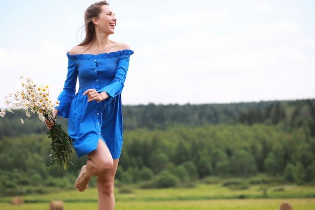 Young cute girl run in a village field at sunset