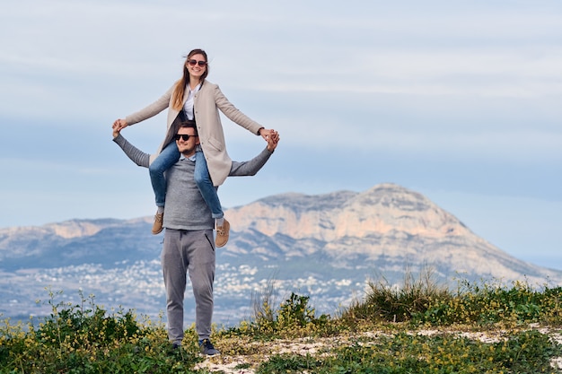 Young cute girl sitting on shoulders of her boyfriend