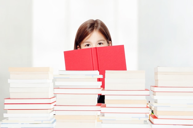 Young cute girl sitting at the table and reading a book