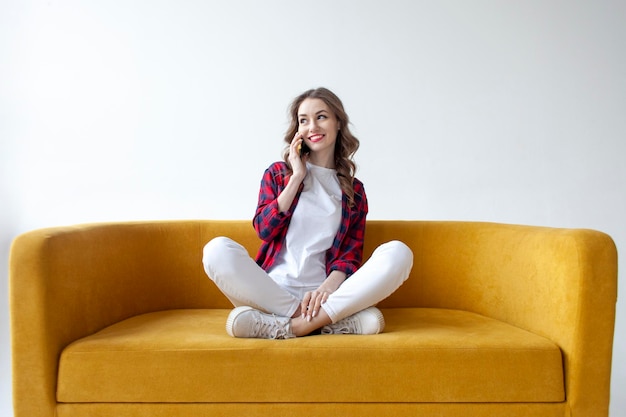 Young cute girl talking on the phone on soft comfortable sofa woman communicates