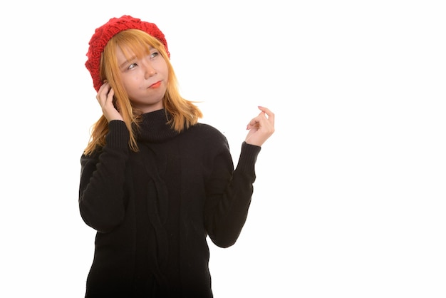 Young cute pensive Asian woman wearing hat while thinking