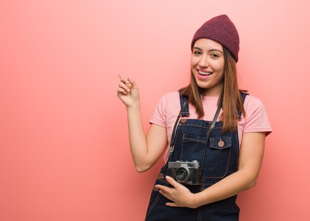 Young cute photographer woman pointing to the side with finger