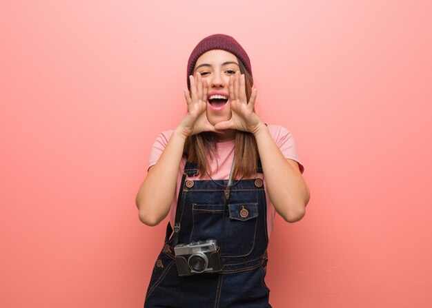 正面に幸せな何かを叫んでいる若いかわいい写真家の女性