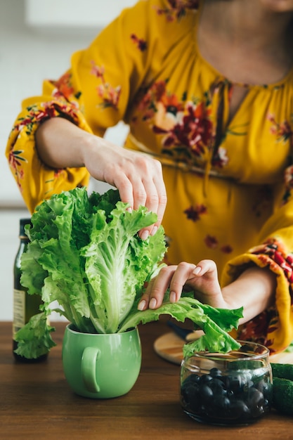 Young cute pregnant girl preparing vegetable salad in the kitchen