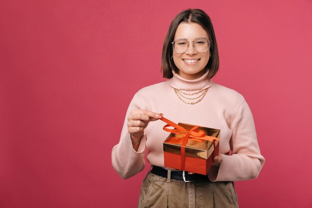 Young cute short haired woman is holding a red wrapped gift box