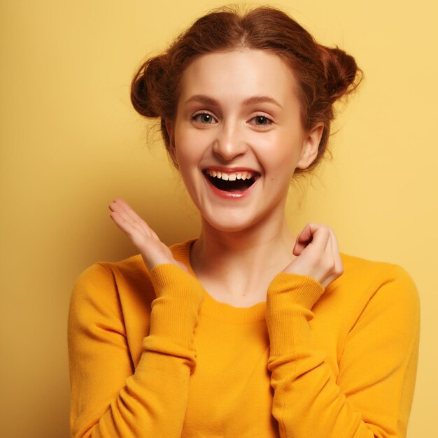 Young cute smiling redhair girl on yellow background happy time