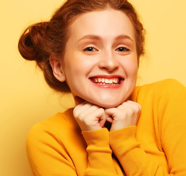 Young cute smiling redhair girl on yellow background