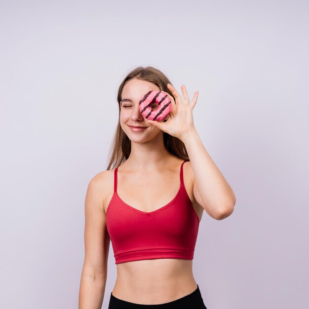 Young cute sport woman eating a donut cake in studio background