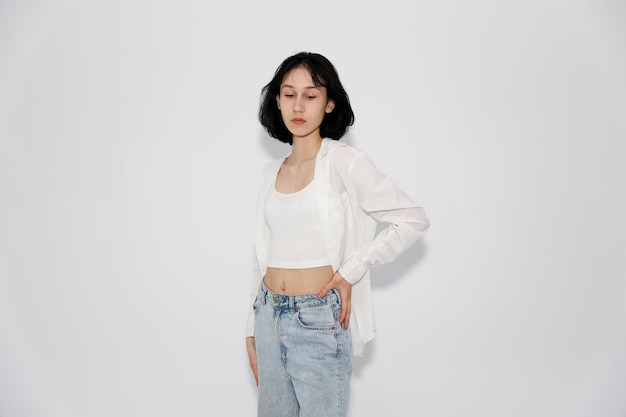 Young cute teen girl in jeans and shirt on a white background