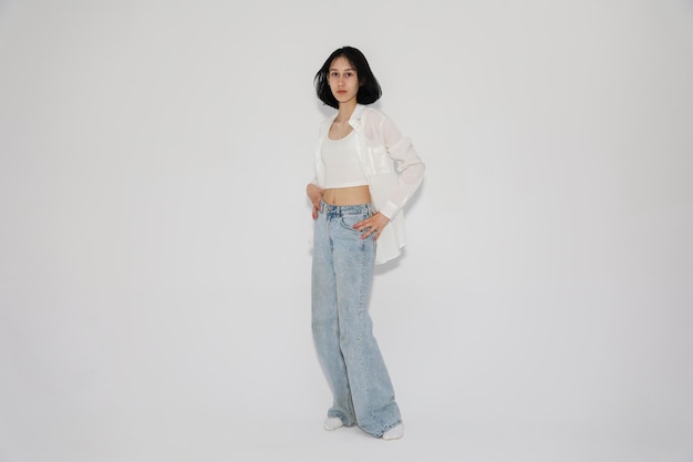 Young cute teen girl in jeans and shirt on a white background