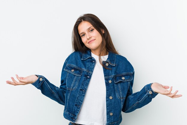 Young cute woman doubting and shrugging shoulders in questioning gesture.