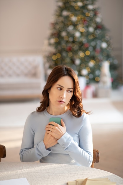 Young cute woman in grey sweater feeling sad