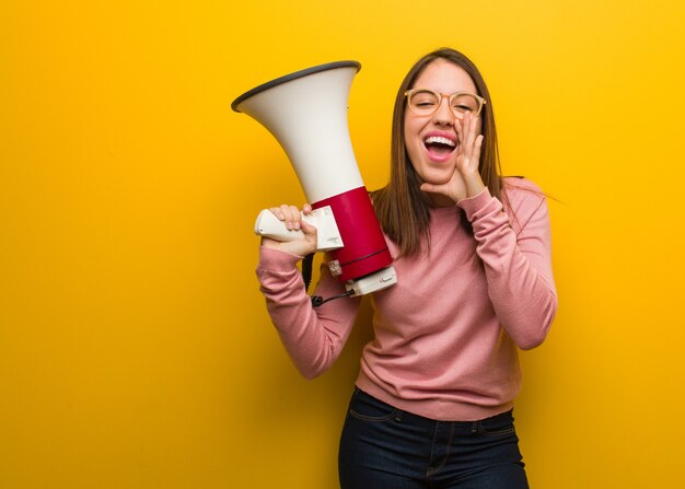 Young cute woman holding a megaphone shouting something happy to the front