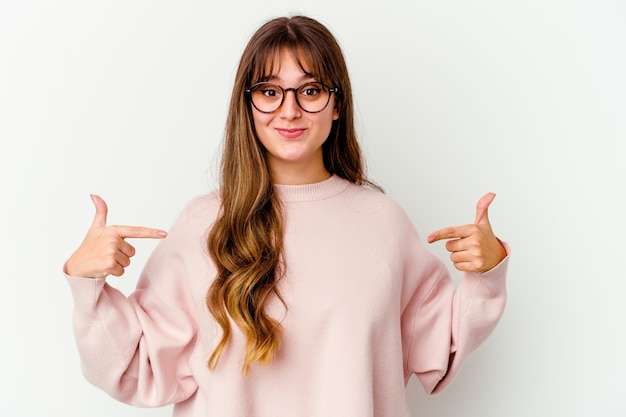 Young cute woman isolated on white wall person pointing by hand to a shirt copy space, proud and confident