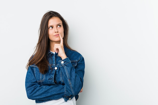 Young cute woman looking sideways with doubtful and skeptical expression.