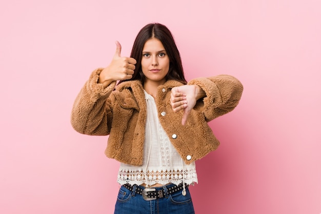 Young cute woman showing thumbs up and thumbs down, difficult choose concept