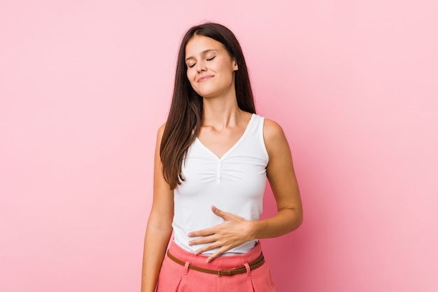 Young cute woman touches tummy, smiles gently, eating and satisfaction concept.