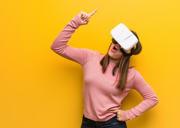 Young cute woman wearing a virtual reality goggles having a great idea