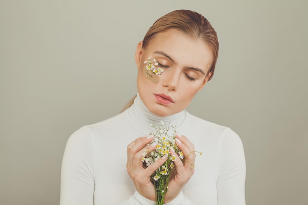 Foto giovane donna carina con fiori di margherite su sfondo bianco concetto di speranza