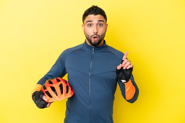 Young cyclist arab man isolated on yellow background intending to realizes the solution while lifting a finger up
