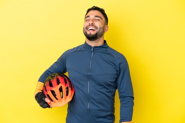 Young cyclist arab man isolated on yellow background laughing