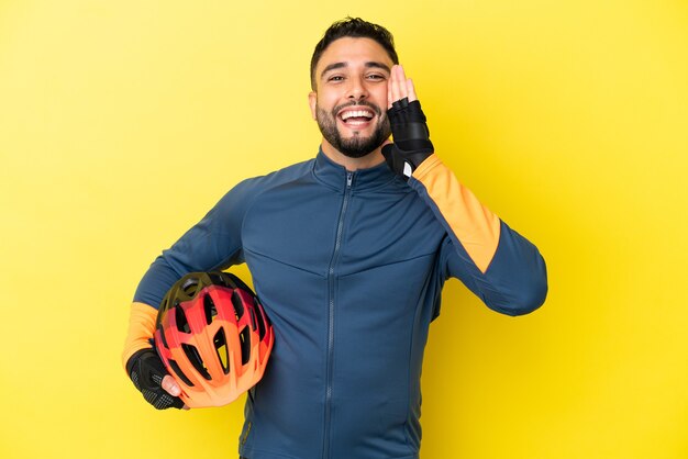 Young cyclist arab man isolated on yellow background shouting with mouth wide open