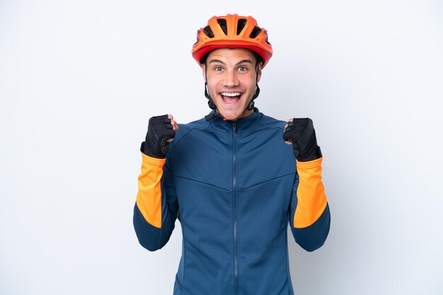 Young cyclist caucasian man isolated on white background celebrating a victory in winner position