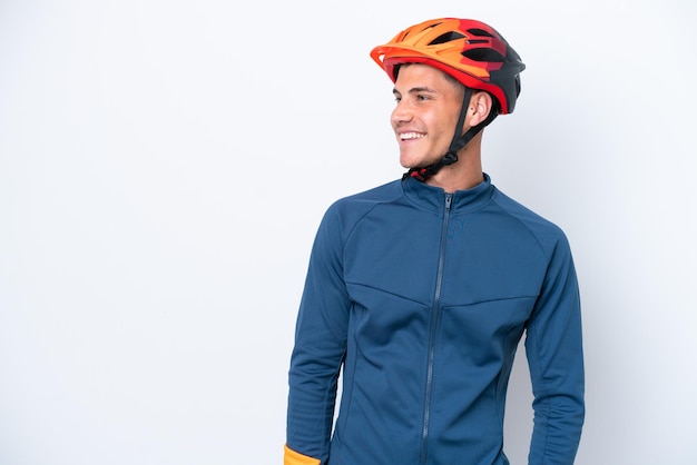 Young cyclist caucasian man isolated on white background looking to the side and smiling