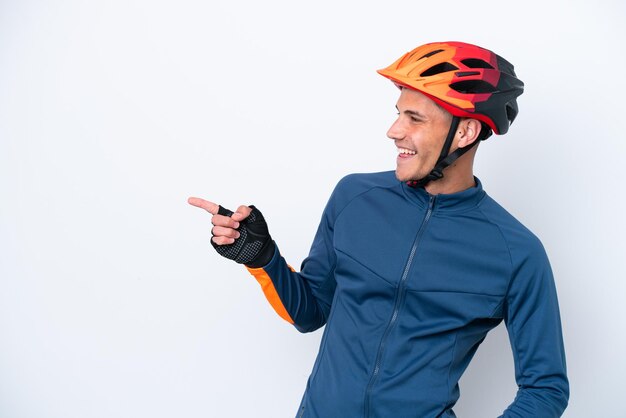 Young cyclist caucasian man isolated on white background pointing finger to the side and presenting a product