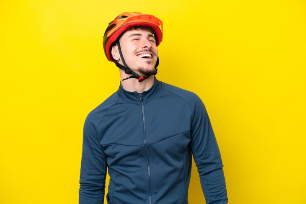 Photo young cyclist caucasian man isolated on yellow background laughing